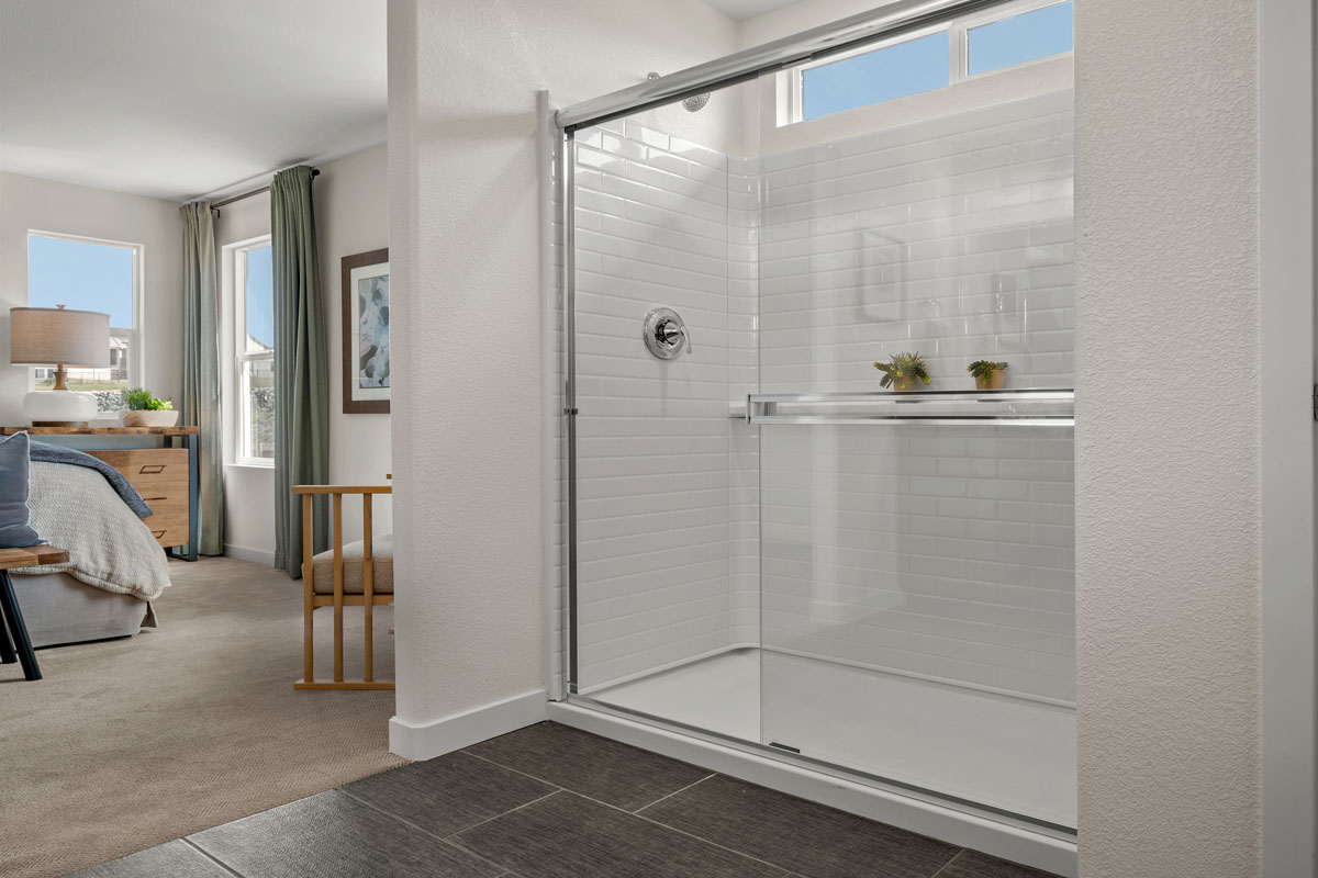 Walk-in shower with fiberglass surround and sliding doors at primary bath